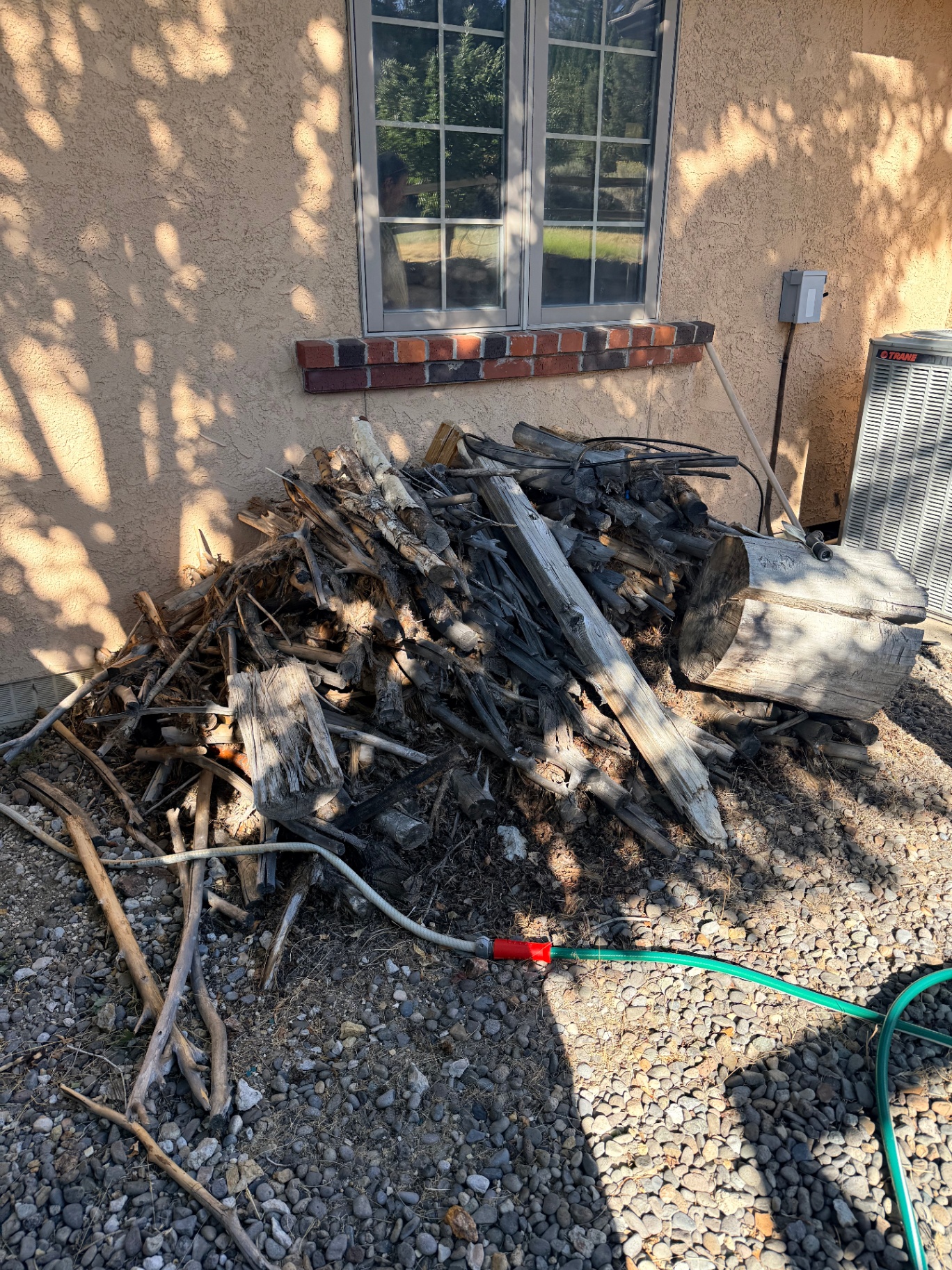 Pile of wood and branches beside a house before removal