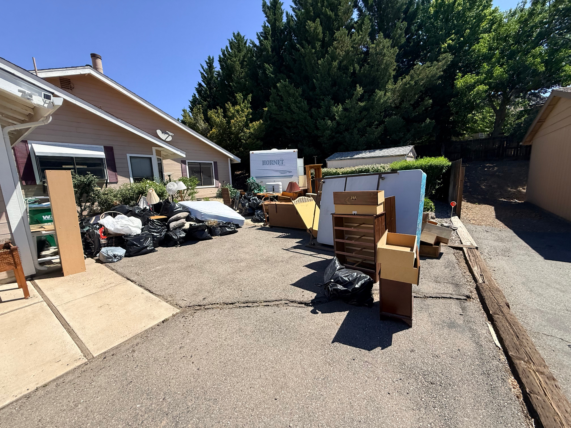 Driveway piled with furniture, boxes, and junk before removal